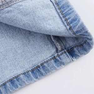 Dettaglio macro dell'abito midi in denim azzurro con doppia cucitura e trama del tessuto