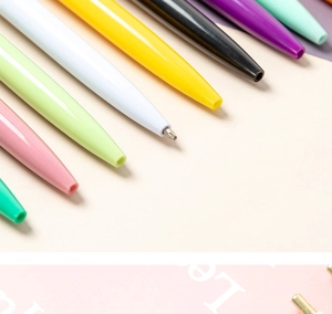 Close-up of colorful plastic click ballpoint pen tips in various vibrant pastel shades.