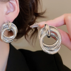 Detail of silver layered metal stud earrings with frosted texture shown on model