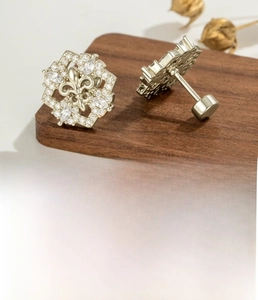 Detailed view of coffee gold fleur-de-lis earrings made of titanium steel and zircon