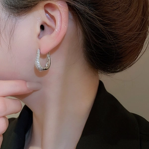 Vue détaillée de créoles argentées en U serties de zircons portées par un mannequin