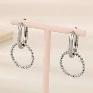 Detail view of silver twisted hoop earrings on a minimalist display stand with high polish