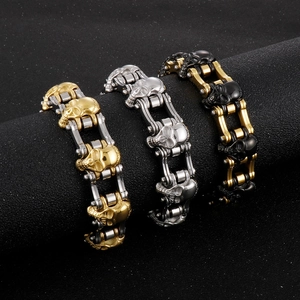 Three punk skull bracelets in gold, silver, and black finishes on a dark display stand
