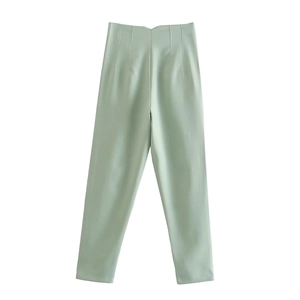 Detail view of high-waisted mint green straight-leg trousers with center pleat details
