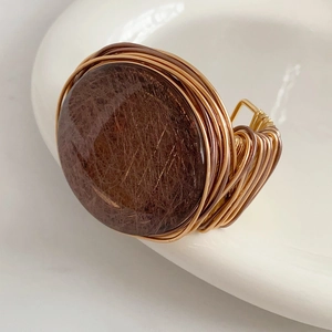 Macro detail of handmade wire-wrapped gold bracelet with brown resin gemstone