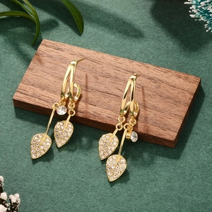 Elegant gold leaf tassel earrings with white rhinestones on green textured background