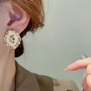 Close-up of vintage gold portrait earrings with pearls and enamel on model's ear