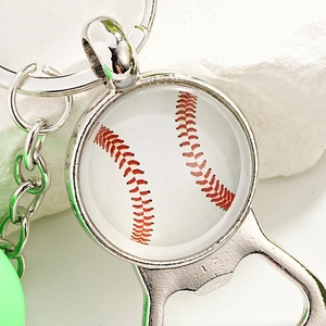 Close-up of a metal baseball keychain bottle opener with detailed red stitching patterns