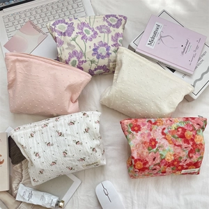 Flat lay of five floral printed canvas cosmetic bags with different vintage patterns