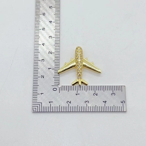 Gold aircraft brooch with sparkling zircons and scale showing 2.4cm length measurement