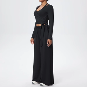 Détail du haut cache-cœur noir à manches longues et du pantalon de yoga large taille haute