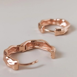 Macro shot of rose gold S925 sterling silver hoop earrings with irregular hammered texture