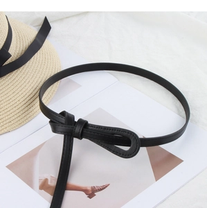 Detail of minimalist black thin waist belt featuring a knot design on white textured fabric