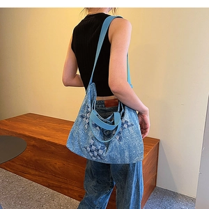 Detailed view of blue denim tote bag featuring handcrafted star patchwork and wide strap