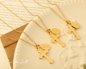 Vue détaillée des pendentifs croix dorée et médaille ovale sur une assiette en porcelaine
