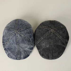Detail of washed denim newsboy caps in light blue and charcoal grey with yellow stitching