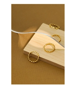 Macro view of four gold beaded S925 sterling silver rings displayed on wood surface