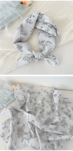 Detail of floral square scarf showing tied style and flat layout on soft fabric