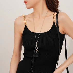 Détail d'un collier chaîne à billes argentée avec pendentif sac noir et pampille