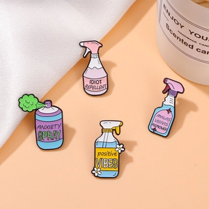 Close-up of four colorful enamel pins with funny spray bottle designs and positive quotes