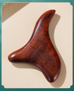 Close-up of sandalwood massage tool with smooth ergonomic edges and natural wood grain
