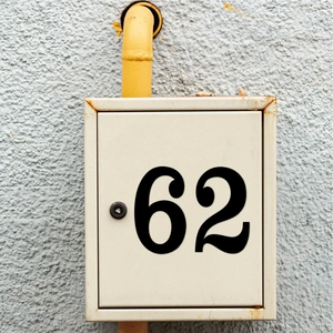 Détail de l'autocollant industriel numéro 62 sur un boîtier métallique beige avec rouille