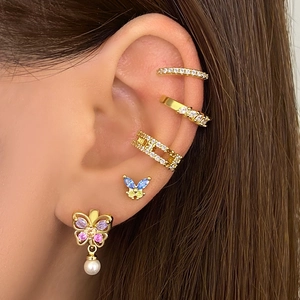 Detailed close-up of a model wearing butterfly stud earrings and gold ear cuffs set