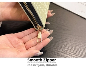 Detail view of the smooth golden zipper and embossed leather texture on mint green wallet