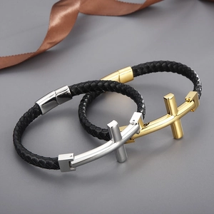 Gros plan d'un bracelet en cuir tressé noir avec breloques croix dorées et argentées