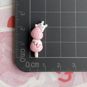 Detailed macro view of pink resin strawberry rabbit charm beside a centimeter ruler scale