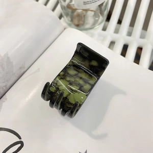 Détail d'une pince à cheveux à 6 dents avec un motif marbré vert foncé et noir