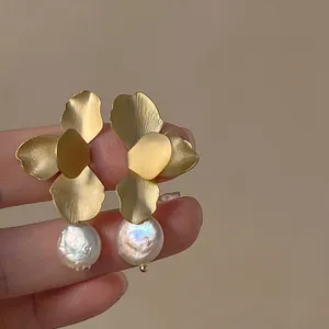 Détail de boucles d'oreilles fleurs en argent 925 avec métal brossé et perles baroques