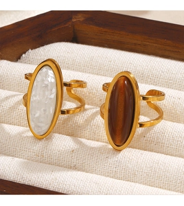 Detail of gold oval rings featuring tiger eye stone and white shell inlay on display