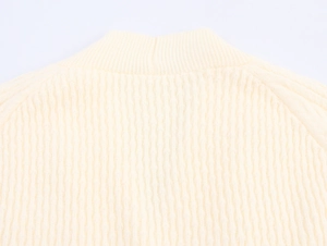 Detail of cream V-neck knit sweater showing ribbed texture and raglan sleeve construction