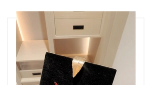 Macro view of a delicate golden leaf ornament on a black velvet evening clutch bag