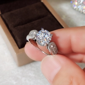 Close-up of a three-stone classic engagement ring with round and pear-shaped crystals
