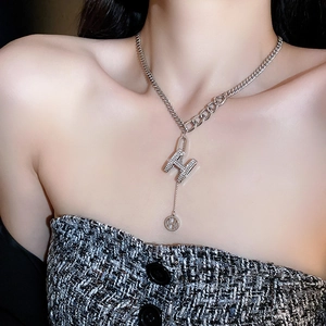 Macro shot of silver-toned chain necklace with pavé-set diamond H letter pendant