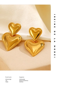 Detail of 18K gold-plated double heart earrings resting on elegant white silk fabric
