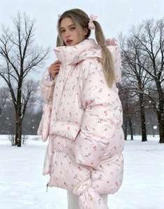 Pink floral puffer jacket with matching neck-strap gloves against a snowy forest