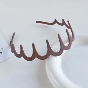 Close-up of a brown wavy leopard print headband with teeth on a white display plate