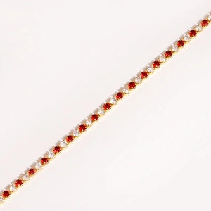 Macro detail of tennis bracelet with red and clear cubic zirconia in gold plating