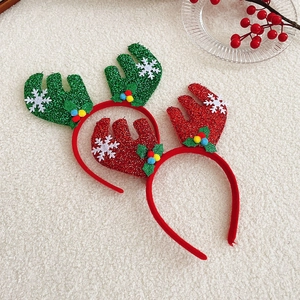 Detail of red and green sequined reindeer antler headbands on white faux fur background