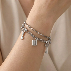 Detail of silver double-layered bracelet with padlock and vintage key charms on wrist