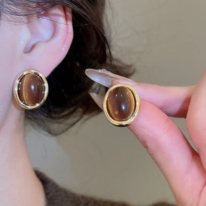 Detail of 18k gold plated tiger eye stud earrings shown worn and held for scale
