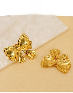 Detail of gold bow earrings in titanium steel showing 3D ribbon texture and back closure