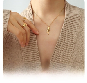 Detail of 18K gold plated rose flower necklace and ring set on model in beige sweater