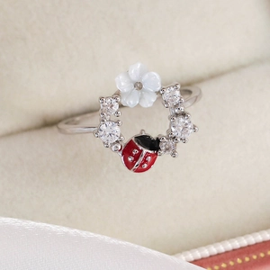 Detail of silver floral ring with a red enamel ladybug and sparkling white zircons