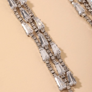 Macro detail of silver tassel earrings with trapezoidal cubic zirconia and claw setting