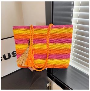 Detail showing colorful woven straw tote with pink orange stripes and decorative tassel