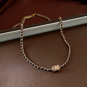 Close-up of golden leather-woven chain with a crystal-encrusted cylinder pendant